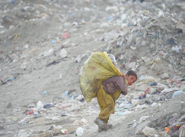 کابل: کوڑا کرکٹ جمع کرنے والا افغان بچہ کوڑے کا تھیلہ اٹھائے جا رہا ہے