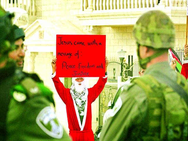 غزہ: فلسطینی شخص سانتا کلاز کا لباس پہنے اسرائیلی فوجیوں کے سامنے مظاہرہ کر رہا ہے