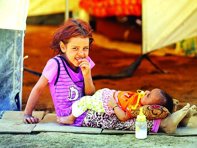 بغداد: بے گھر بچی اپنی چھوٹی بہن کے ہمراہ کیمپ میں کھیل رہی ہے