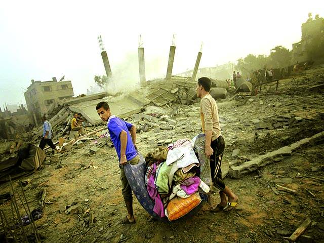 غزہ: فلسطینی اسرائیلی فوج کی بمباری سے تباہ شدہ عمارت سے اپنا سامان لیکر جارہے ہیں