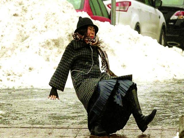  ٹورنٹو: برف باری میں راہگیر خاتون سڑک پر جاتے ہوئے پھسل کر گر رہی ہے